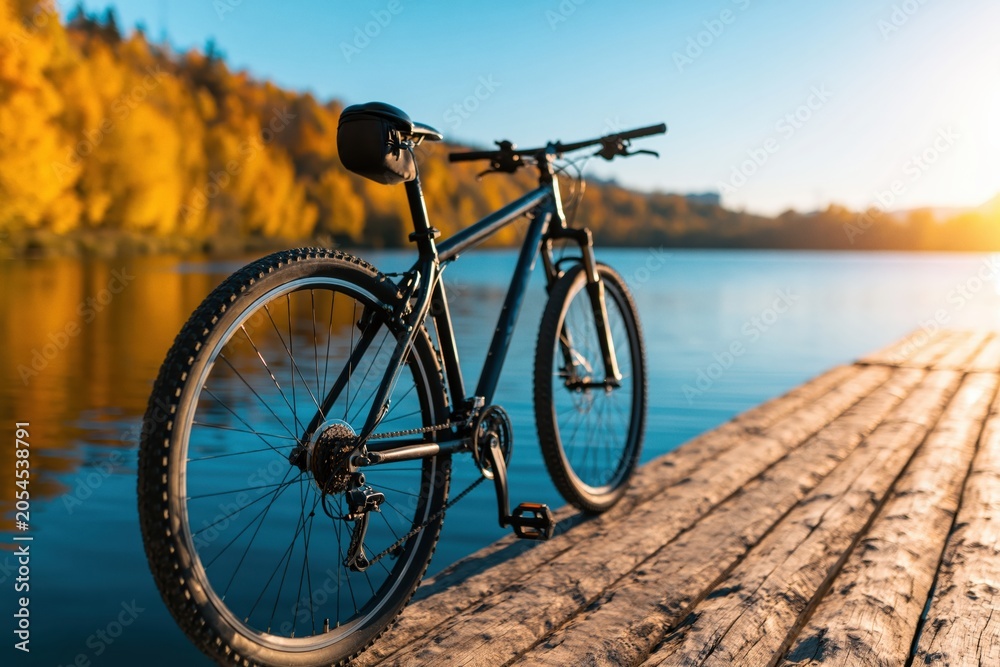 Fototapeta premium Bicycle mountain bike on wooden pier by autumn lake nature fall outdoor cycling