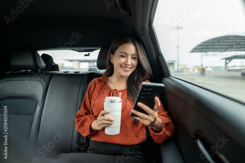 Asian woman commuting in car backseat using smartphone