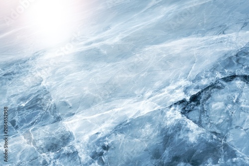 A serene icy landscape with translucent frozen water and cracks, illuminated by soft sunlight reflecting off the surface.