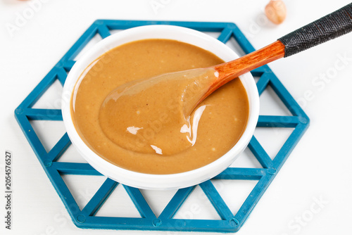 Pure Peanut Butter in Bowl with Wooden Spoon