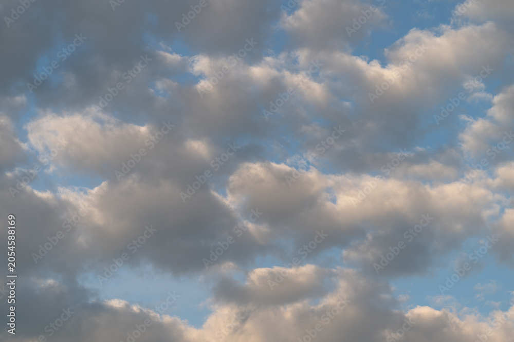 Obraz premium Soft cumulus clouds at golden hour over blue sky