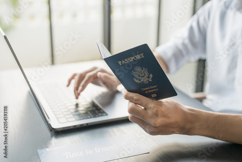 Foto Hand Man Online booking and buying plane tickets using laptop phone and credit c