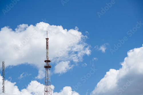 Foto Telecommunication tower rising into blue sky with white clouds