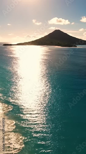 Golden sunset over tropical beach with gentle ocean waves.