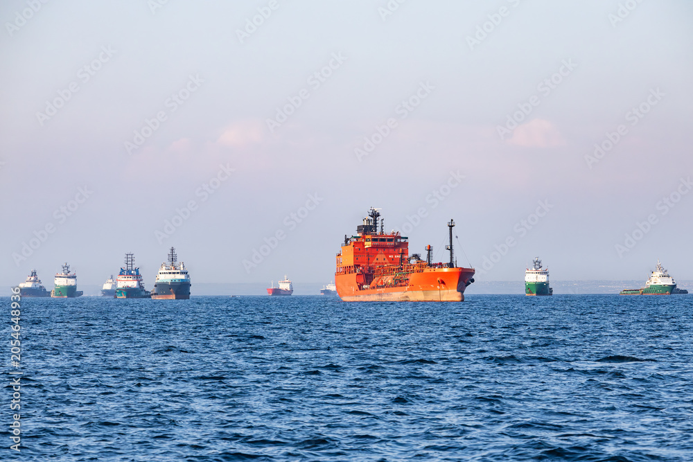 Fototapeta premium Industrial cargo ships and offshore supply vessels anchored at open sea near port harbor maritime terminal area