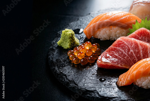 Luxury Japanese sushi and sashimi platter with salmon, tuna, ikura and wasabi on black slate