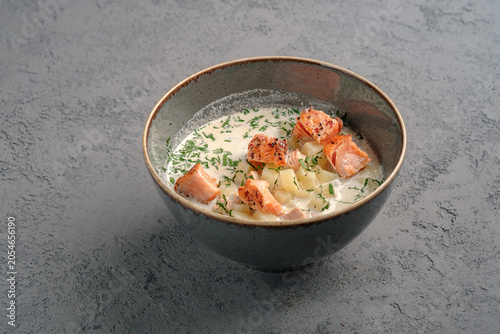 Creamy Finnish salmon soup (lohikeitto) with tender grilled salmon chunks, diced potatoes and fresh dill garnish in rustic bowl. Traditional Nordic fish chowder