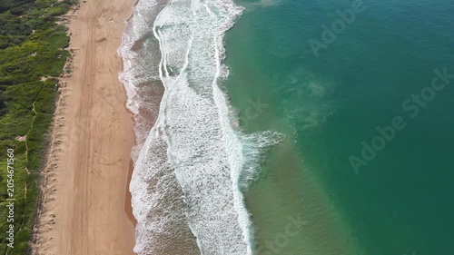 Drone video aerial view of waves crashing onto the shore on a beach in Sydney Australia in Summer 