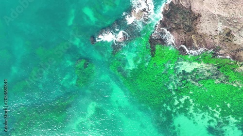 Drone video aerial view of waves crashing onto rocks near a beach in Sydney Australia