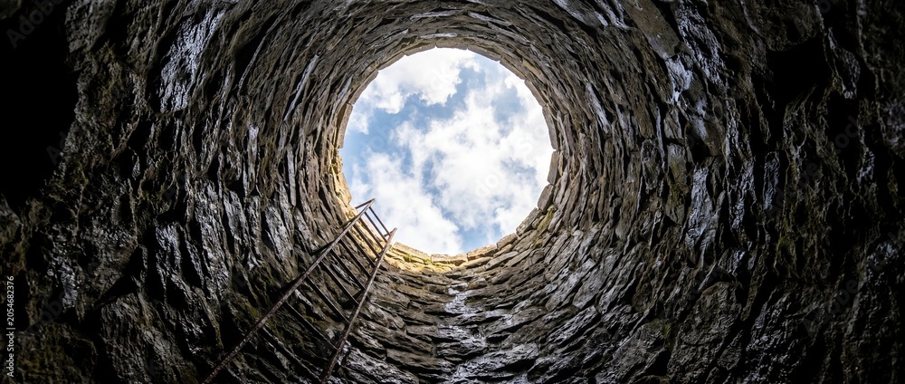 Fototapeta premium View from inside dark well looking up to bright light opening