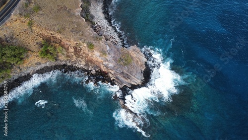 Fotografie Top-Down Aerial View of Ocean Waves Crashing Against Rocky Coastal Cliffs in Mau