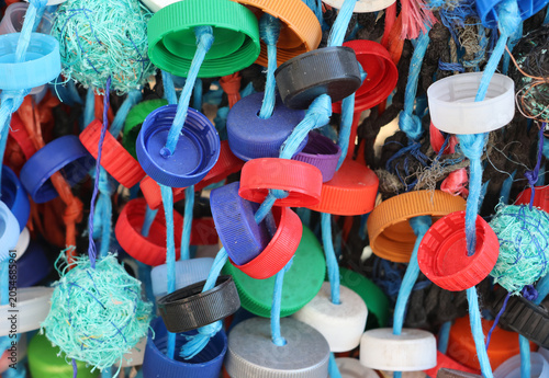 Colorful plastic bottle caps and marine debris strung on blue ropes for environmental awareness