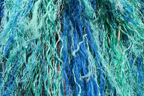 Full-frame texture of frayed and tangled bright blue and teal synthetic marine ropes
