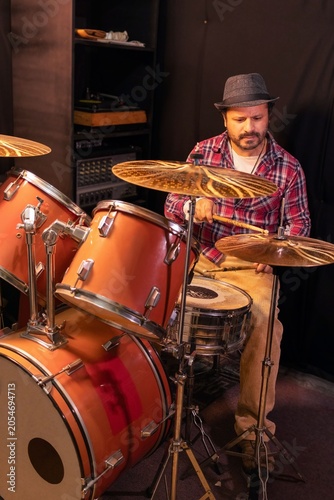 Fotografie A focused male musician playing drums during a rehearsal session in a recording