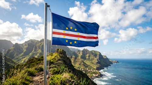 Cape Verde national flag waving on metal pole against green mountainous coastline and blue sky landscape
