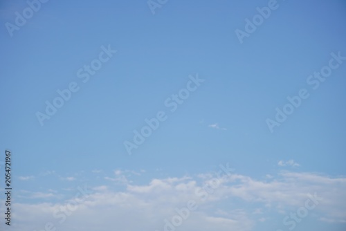 Gentle wispy clouds drifting softly through wide clear blue sky during mid summer