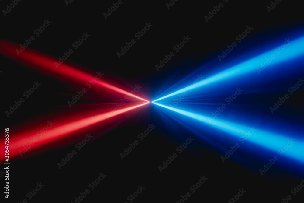Fototapeta premium Red and blue laser beams converge towards a central point on a solid dark background, showcasing optical light effects.