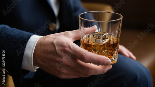 Photos Man holding a glass of whiskey with ice