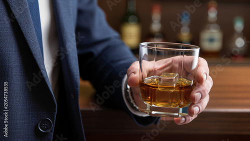 Photos Man holding a glass of whiskey with ice