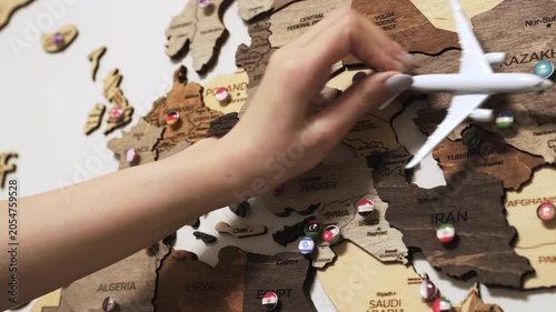 Woman holding airplane above wooden map, travel concept.