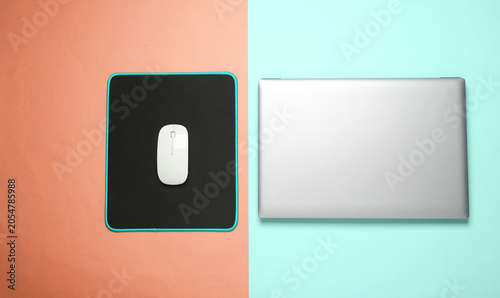 Foto Laptop and PC mouse with PC mouse pad on pink blue background