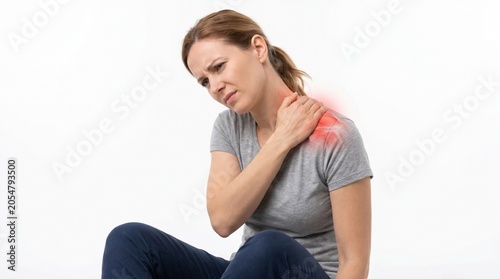 Woman experiencing shoulder pain while sitting on floor in indoor casual setting