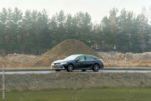Billede på lærred Modern black sedan cruising on busy road