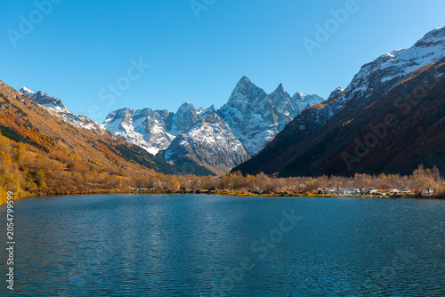 Tumanly Kel lake against of high rocky snow-capped mountains and forested slopes