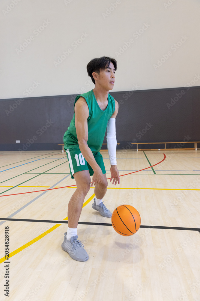 Naklejka premium Orange basketball bouncing near midcourt on hardwood floor with colored court lines, copy space