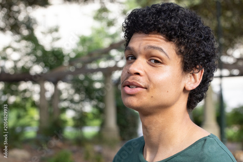 African American male standing turning toward camera in garden under pergola wearing green shirt