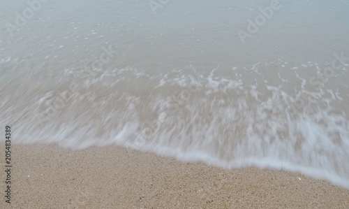 The waves are crashing against the sandy beach