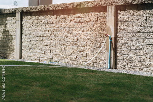Foto Garden hose outdoor faucet stone wall green grass water pipe garden irrigation b