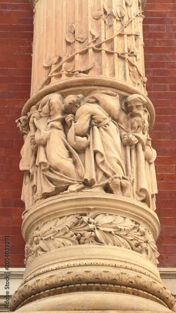Naklejka premium Ornate Terracotta Column Detail with Intricate Figurative and Floral Carvings