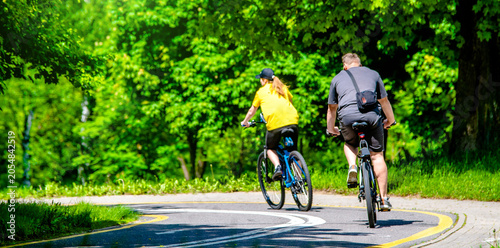 Billede på lærred Cyclists ride on the bike path in the city Park