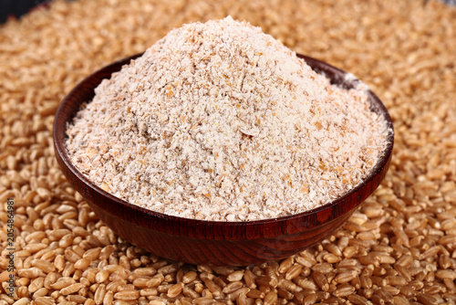 Foto Fresh Whole Grain Rye Flour in Wooden Bowl with Rye Kernels