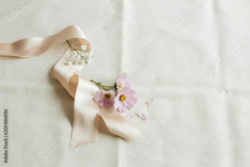 Elegant pink cosmos flowers white baby's breath arranged on a flowing satin ribbon