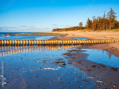 Herbst am Strand der Ostsee mit Buhnen und stürmischer Brandung unter blauem Himmel, Mecklenburg-Vorpommern, Deutschland 