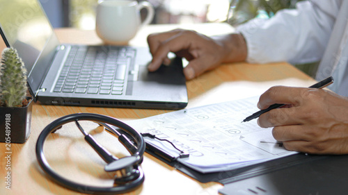 Cuadro en lienzo Healthcare professional reviewing medical checklist and patient documentation while working on a laptop in a modern clinic