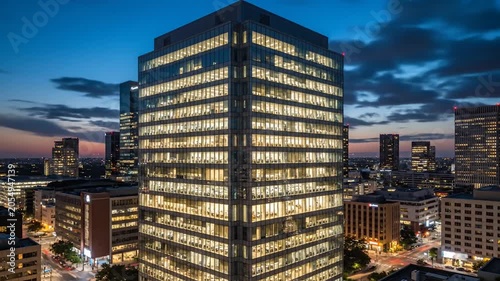Evening Time Lapse of Modern Office Building with Glass Windows and Illuminated Interior Lights in Urban Business District