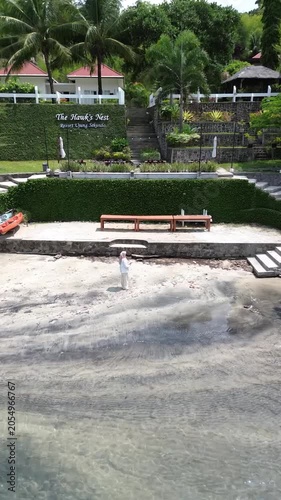 Aerial drone shot of hijab woman standing and walking at the tropical resort near the beach in Weh island, Sabang Indonesia. Travel and holiday concept. Beach vacation in paradise tropical island