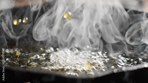 Water droplet falling into hot oil in cast iron pan