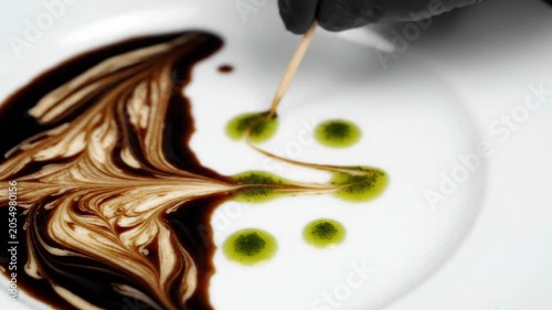 Chef garnishing plate with balsamic glaze and olive oil dots