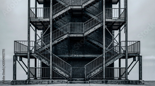 Metal fire escape zigzag stairs on white sky, graphical grey geometry minimalism