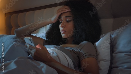 Slika na platnu Sad unwell African American girl scrolling mobile phone feeling headache at nigh