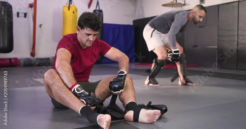 Diverse training partners following strap adjustments and unpacking guards in gym for sparring