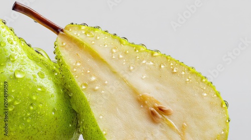Fresh Green Pear Halved and Covered in Water Droplets on a White Background © The Little Hut