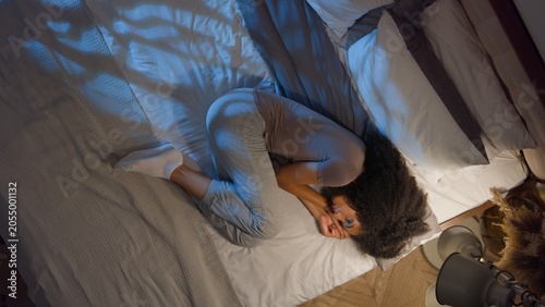 Foto Top view unhealthy unwell African American woman suffering stomach pain lying on