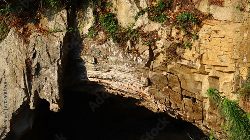 Bild auf Leinwand Stratigraphic Layers and Eroded Rock Formation with Dark Subterranean Cave Entra
