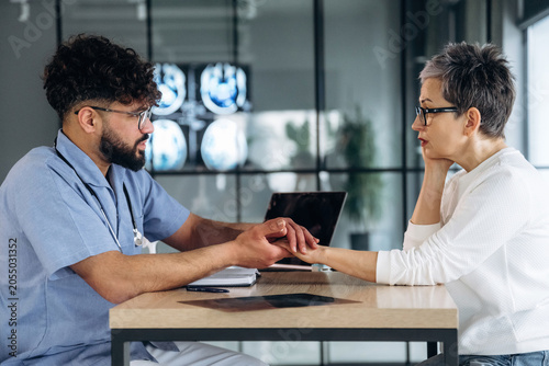 Foto Male healthcare professional in blue scrubs examines female patients wrist at a