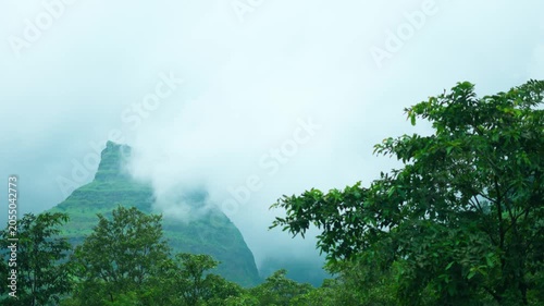 4K Landscape shot of clouds surrounding the green Sahyadri hills during the monsoon season as seen from Maharashtra, India. Scenic view of Western Ghats during the rain. Natural monsoon background.